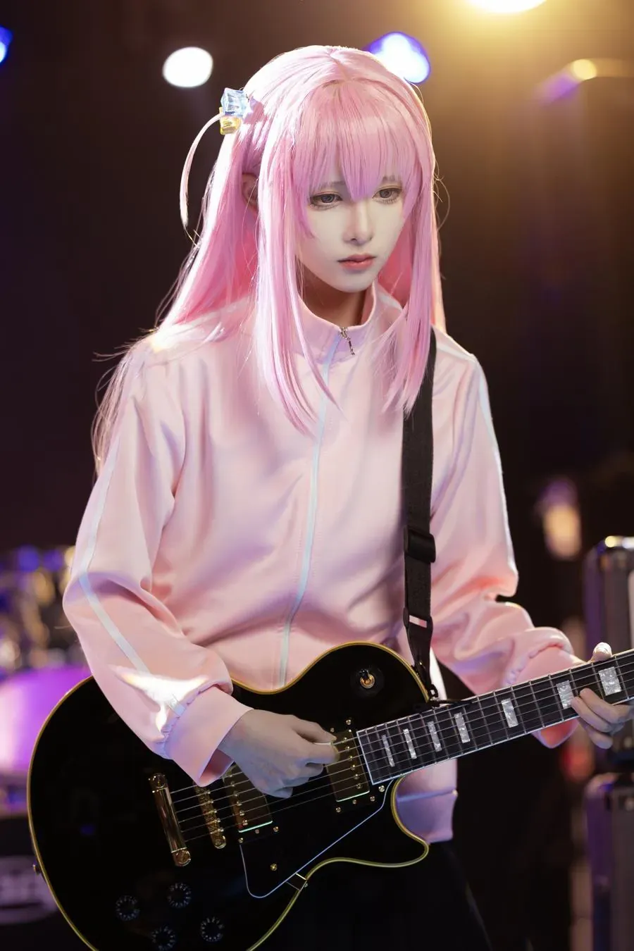 KuukoW海外Coser KuukoW粉色长发Cosplay造型，手持黑色吉他位于舞台空间