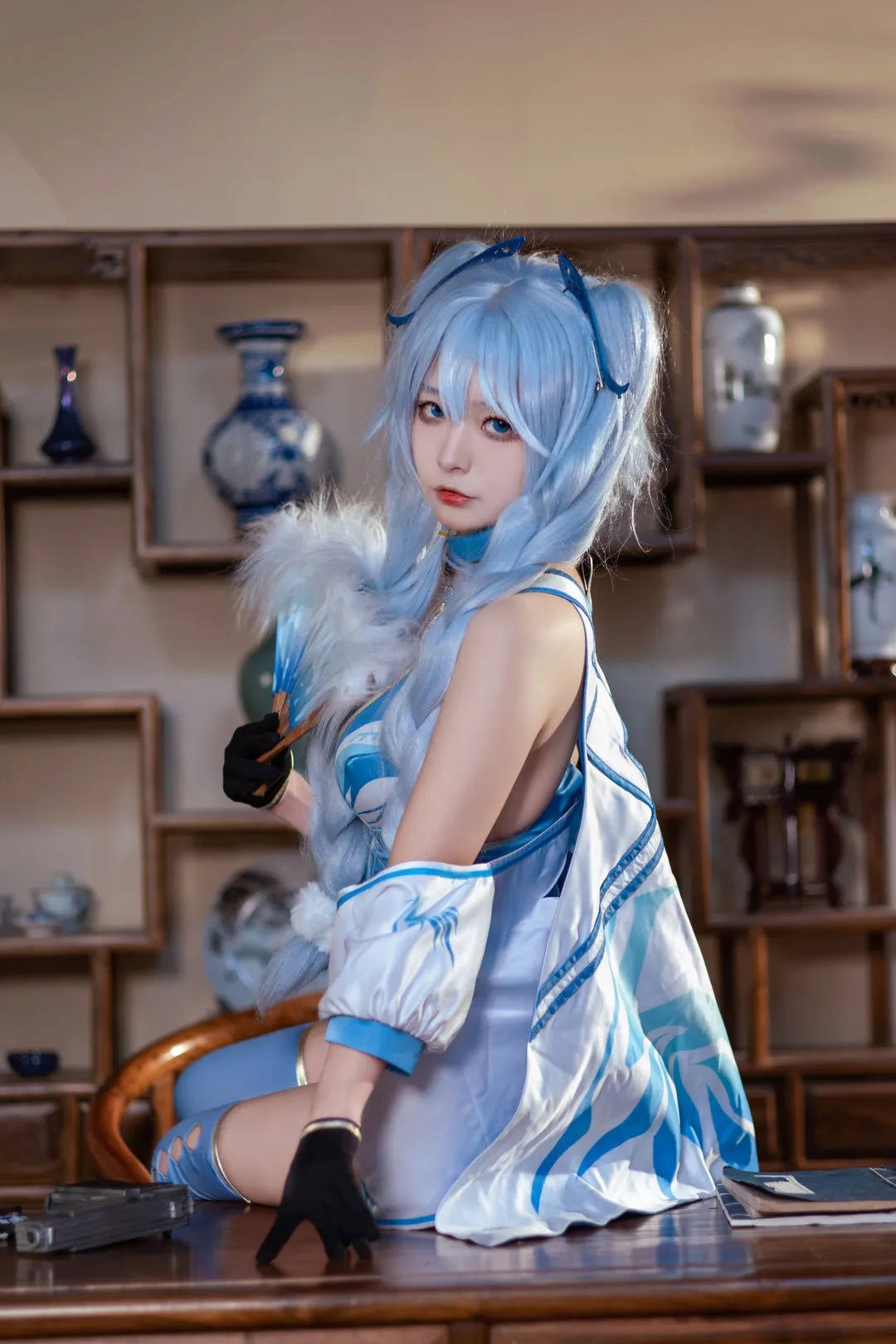 yuuhui玉汇与Kokuhui名称对应｜Cosplay代表作品 浅蓝长发、蓝白服饰与羽毛扇造型，人物坐在木质陈列空间前