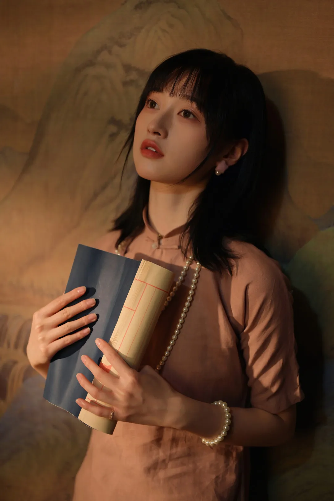 YALAYI雅拉伊海外 YALAYI雅拉伊相关人像照片,人物手持书本,黑色短发造型搭配暖色环境光