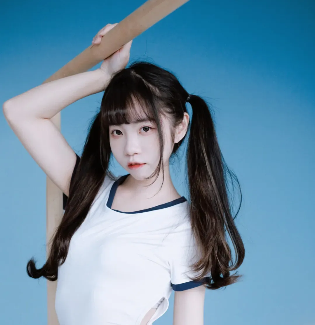 可可小白兔跨语言名称识别与Cosplay作品方向 黑色双马尾齐刘海人物穿白色短袖上衣站在蓝色背景前，一只手臂向上扶住木质横杆