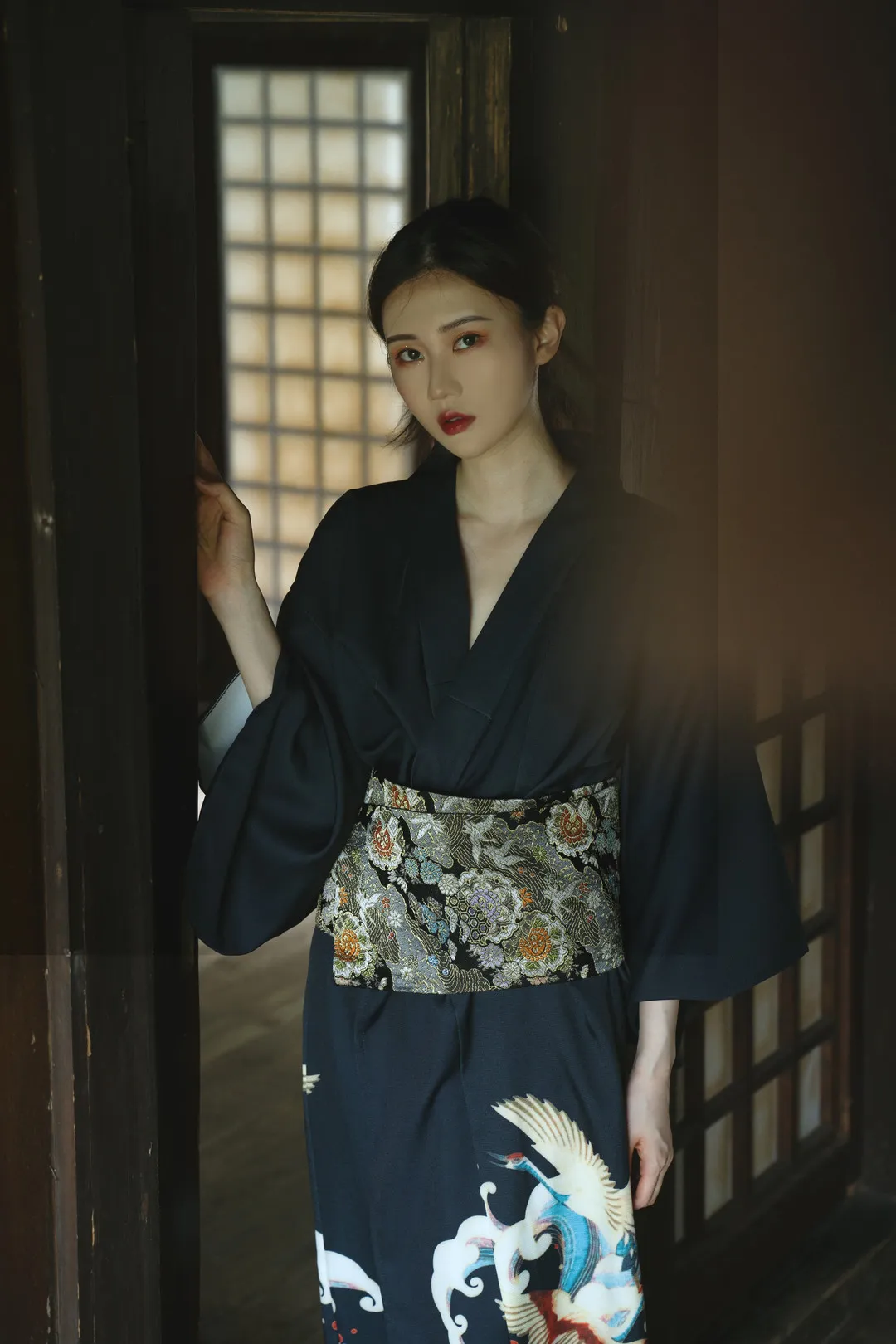 穿着深藏青色仙鹤刺绣和服的女性模特站在日式木格拉门前