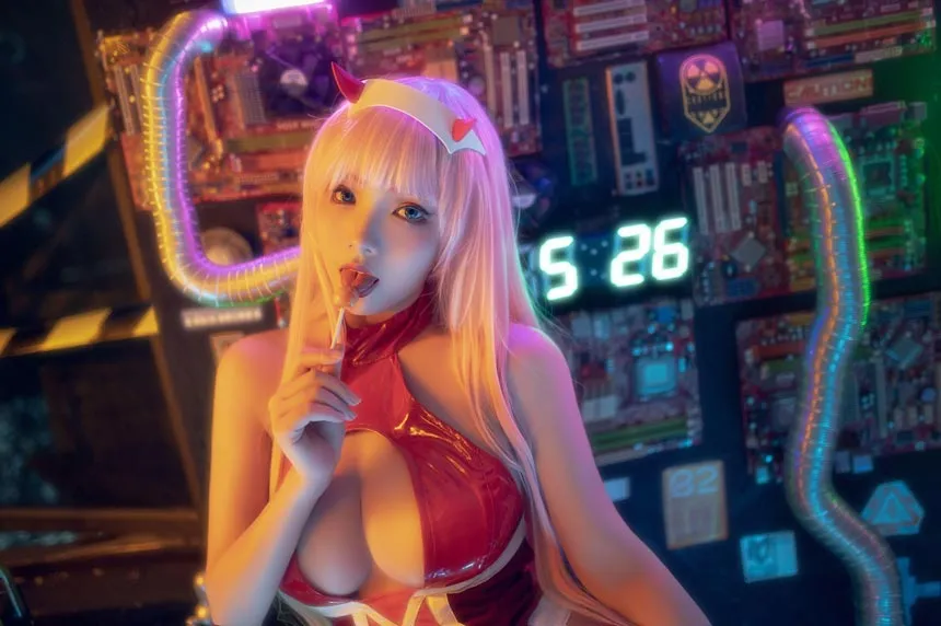 创作者身穿红色高光胶衣佩戴粉色假发咬着棒棒糖的室内特写