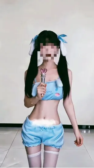 苏小柠身穿浅蓝色卡通图案吊带上衣与短裤,手持粉色爱心手杖站在室内。