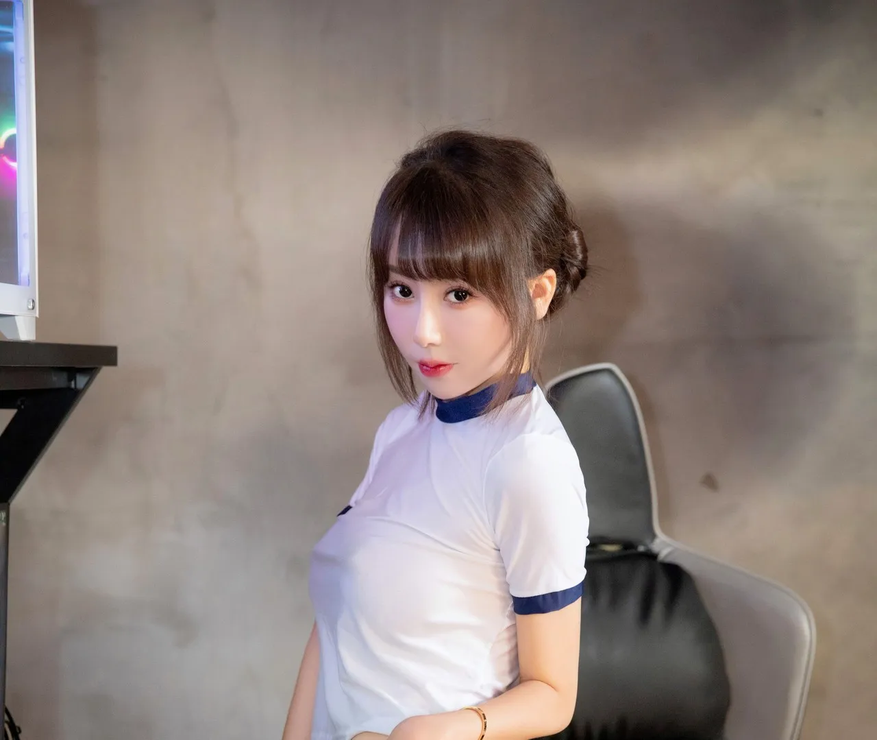 身穿白蓝拼接运动短袖坐在电竞椅旁的侧身特写