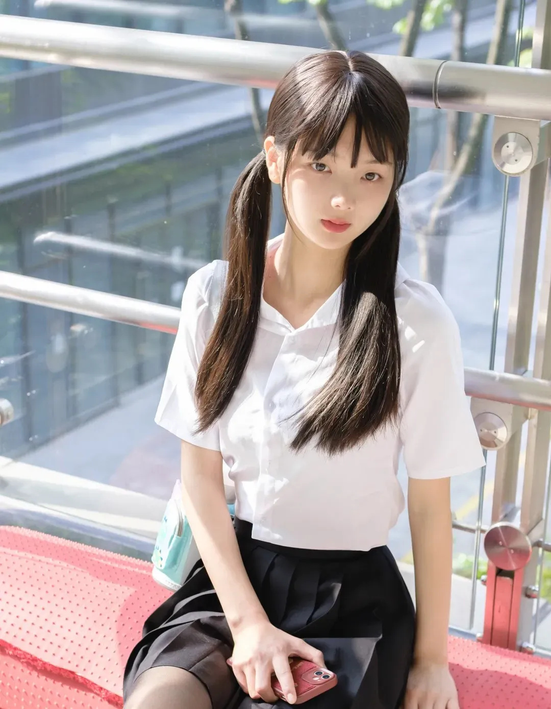 扎双马尾穿白色短袖衬衫与黑色百褶短裙在露台连廊采光处留影