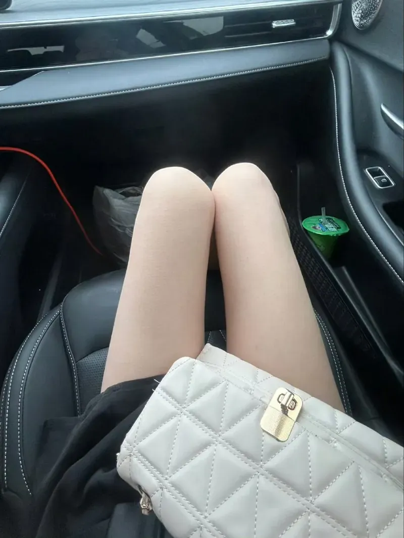 月色跨语言名称辨识 黑色汽车乘客座内的第一视角构图，前景有浅色手袋与人物腿部