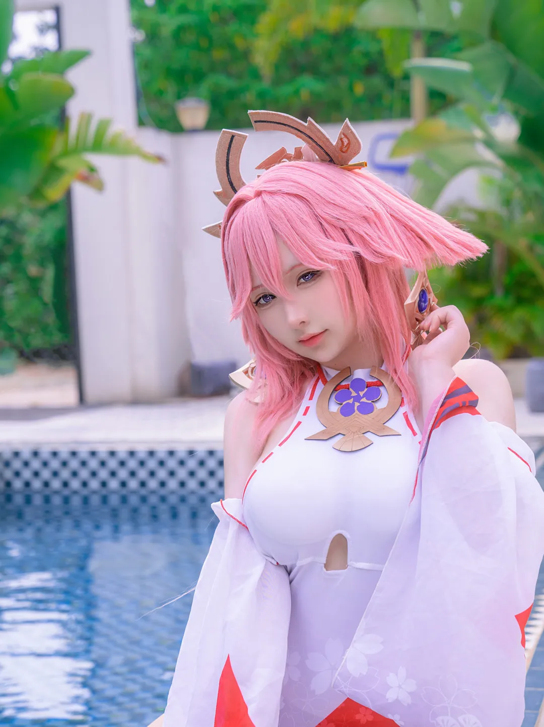 樱梨梨Eriri海外名称识别与Cosplay代表作品 粉色假发人物佩戴金棕色头饰和蓝色耳部装饰，身穿白色红边角色服装，在蓝色泳池旁抬手摆姿势