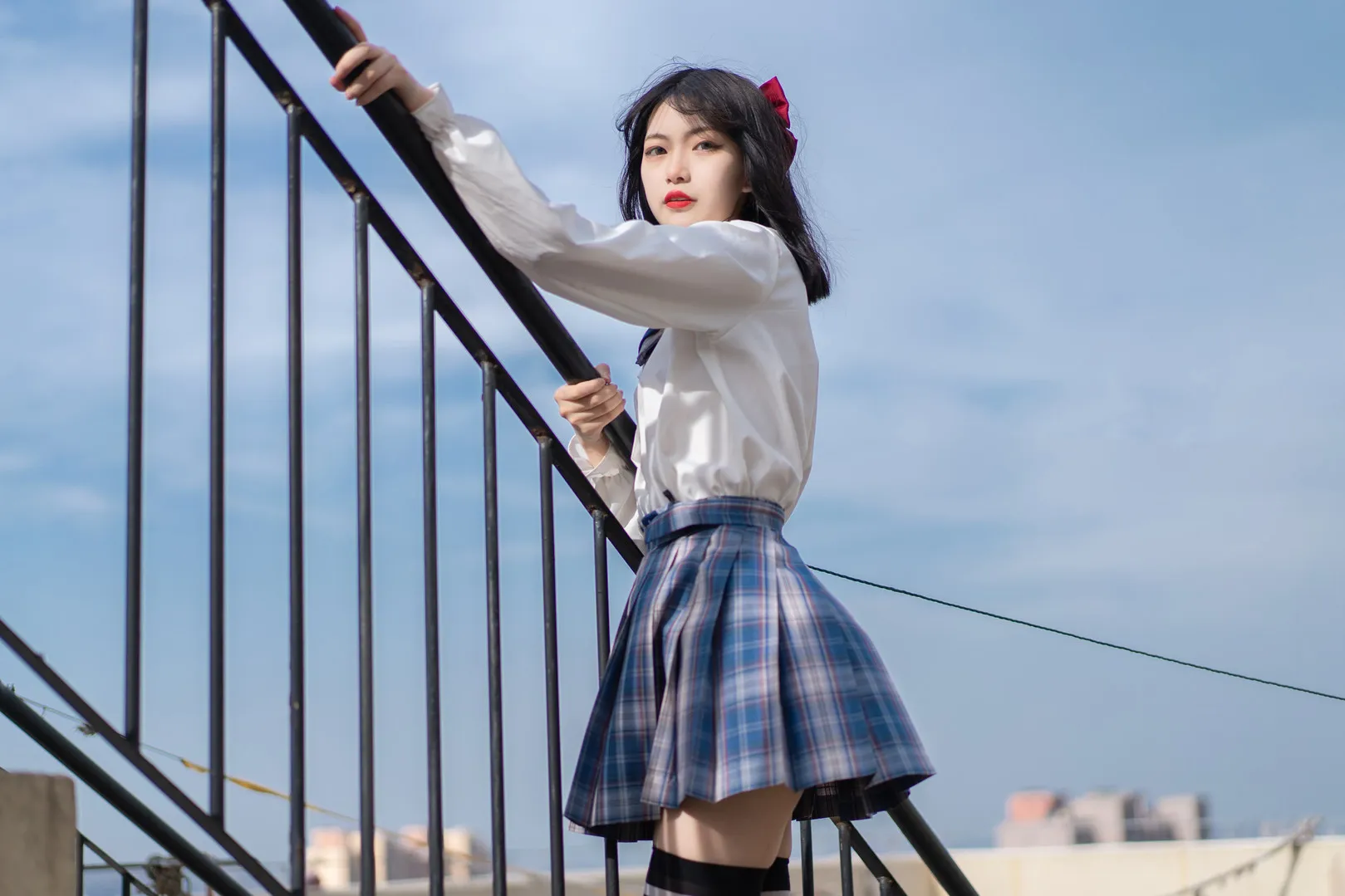 梨瑾瑾 cosplay 海外名称与写真视觉图集导读 梨瑾瑾户外写真造型，黑色短发搭配白色上衣和格纹裙装，站立于栏杆附近，天空背景形成开阔构图。
