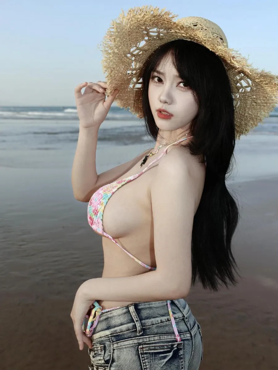 海边沙滩头戴编织草帽身着彩色针织泳装的侧身姿态