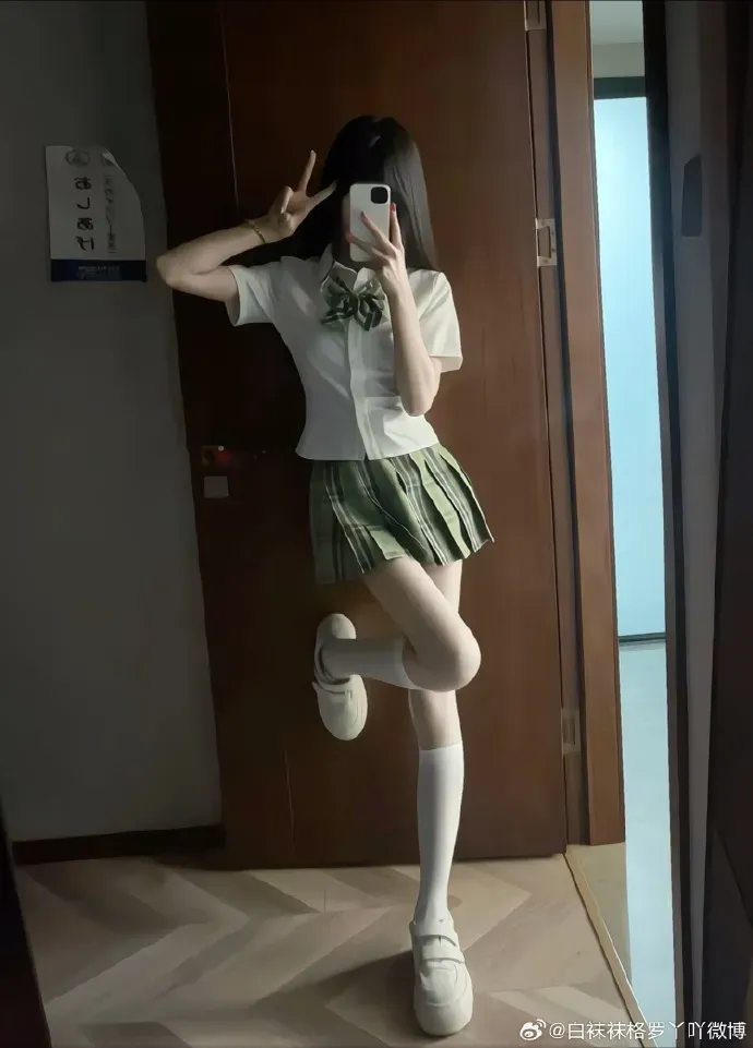 创作者身着浅绿色格纹裙搭配白色中筒袜单腿弯曲站立