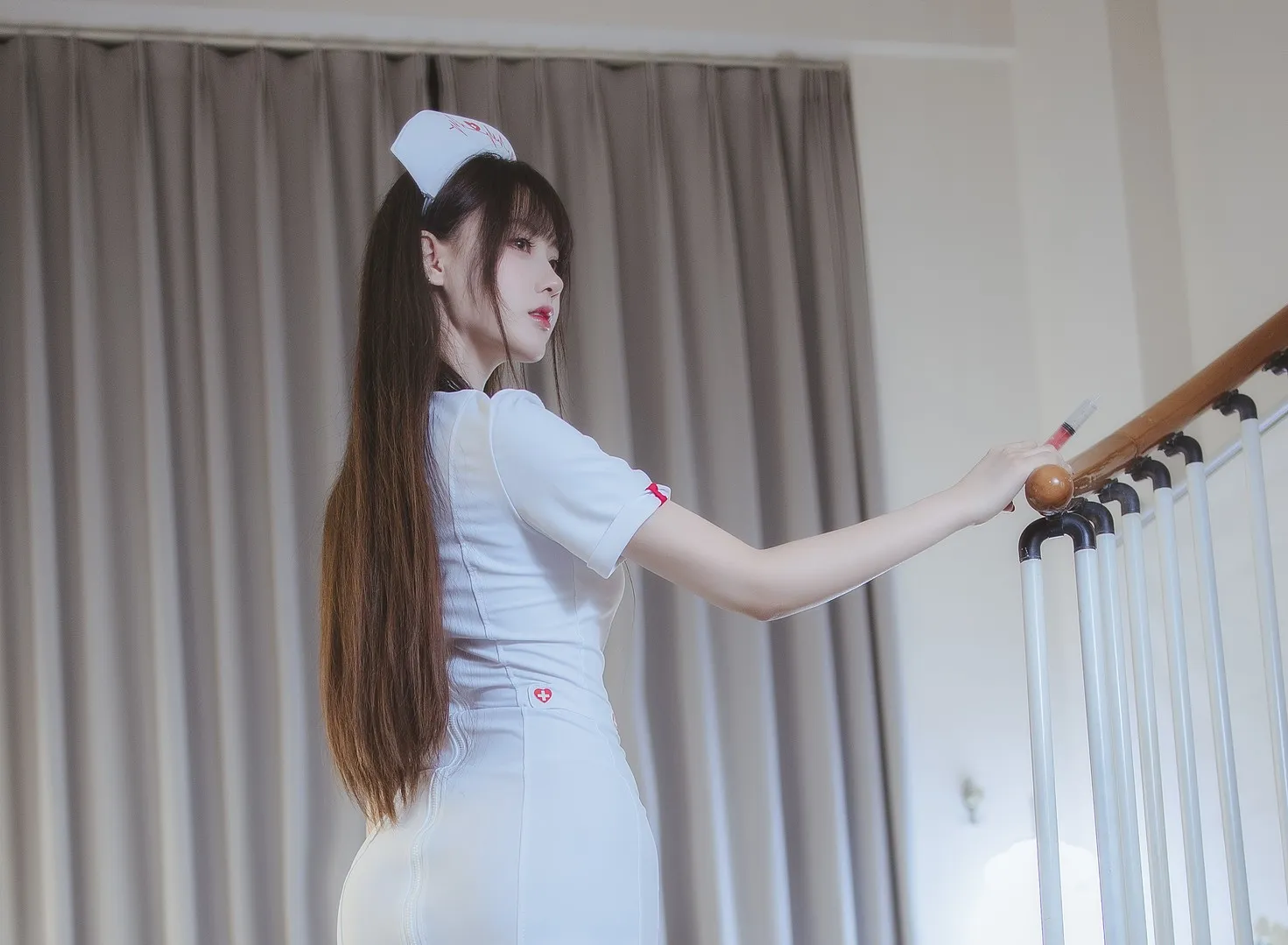 身着白色连体短袖护士服手扶楼梯木质扶手的背侧身立姿