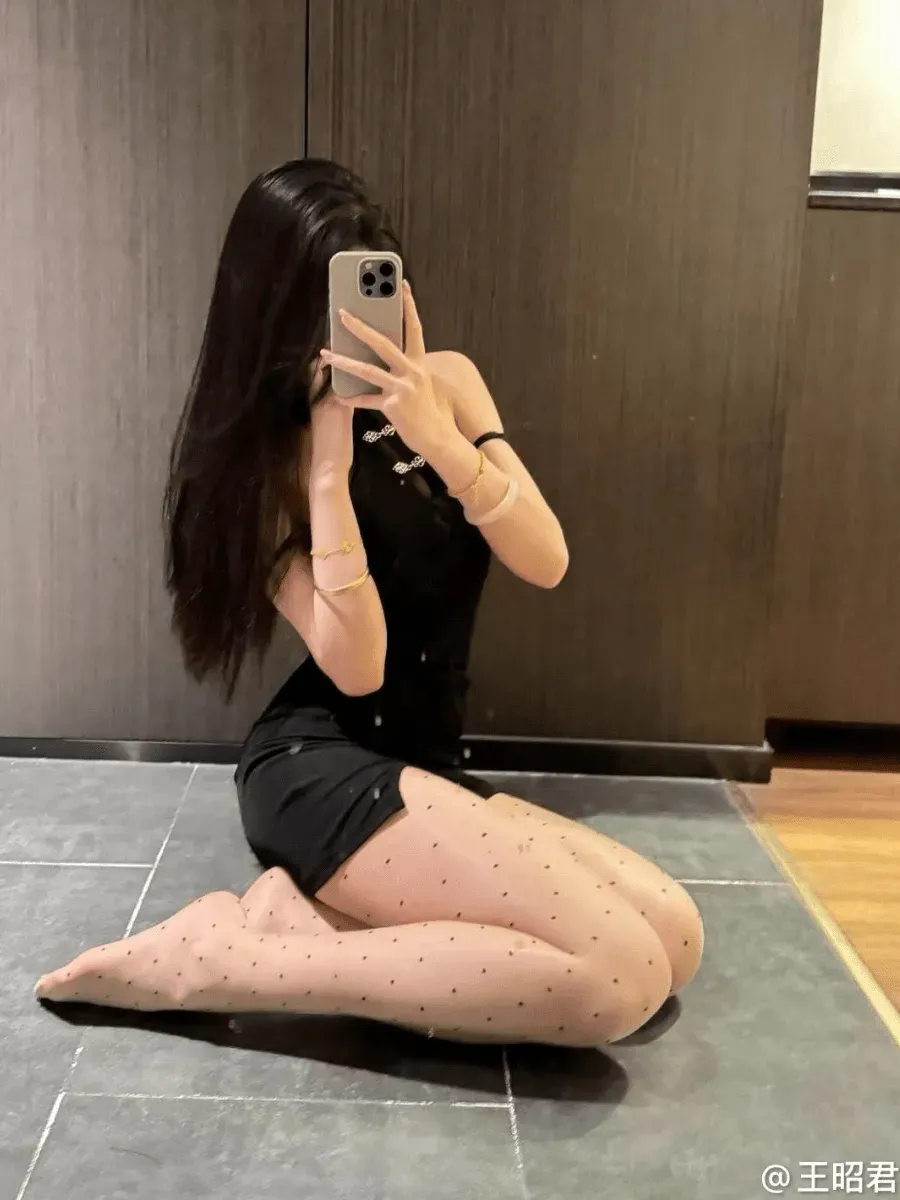 王昭君身穿黑色修身无袖短裙搭配波点丝袜正跪坐于深灰色地砖上对镜自拍