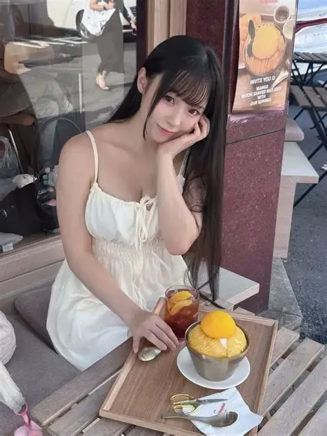 晴兒littlesshine跨语言名称识别与阶段性作品整理 长黑发齐刘海女子穿白色吊带连衣裙坐在户外咖啡座,桌上有黄色水果甜品和饮品
