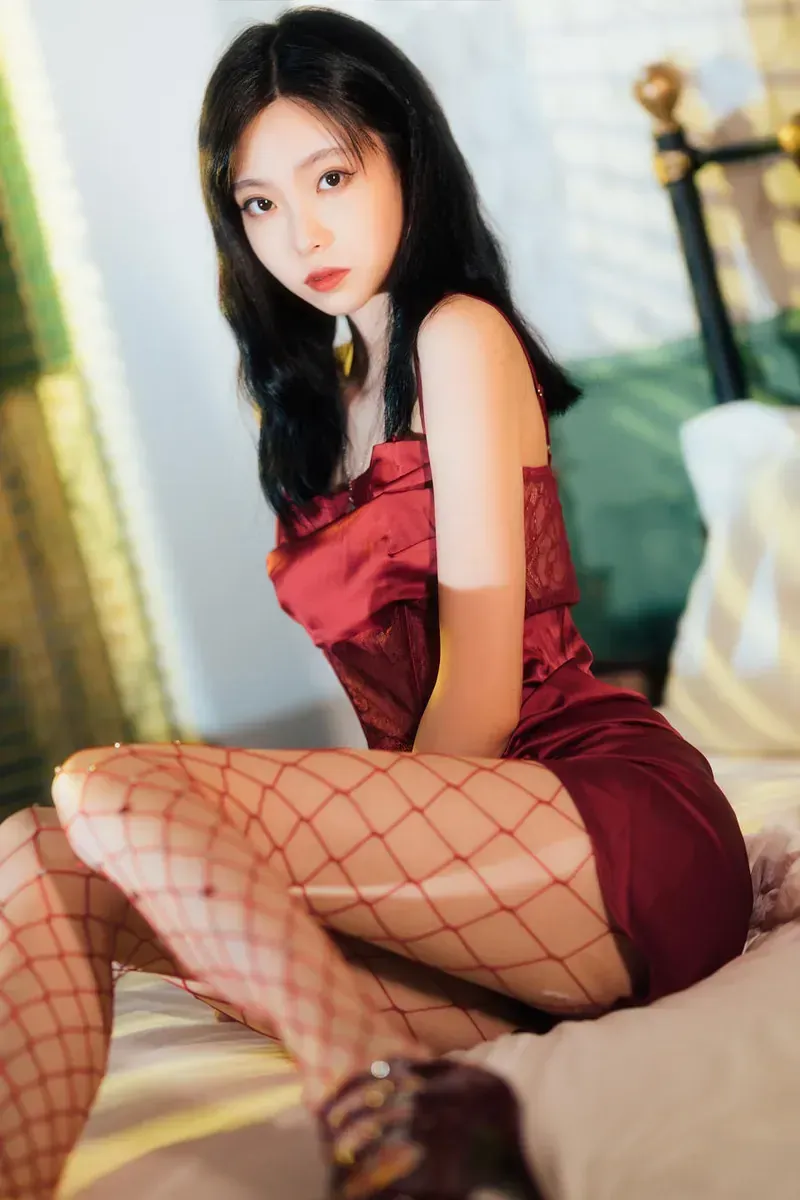 许岚lan_身着深红色吊带丝绒短裙与红色渔网袜的模特侧坐于浅色床榻_01